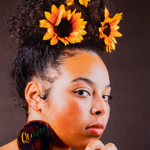 Color photograph of a side profile of a woman with sunflowers in her hair.